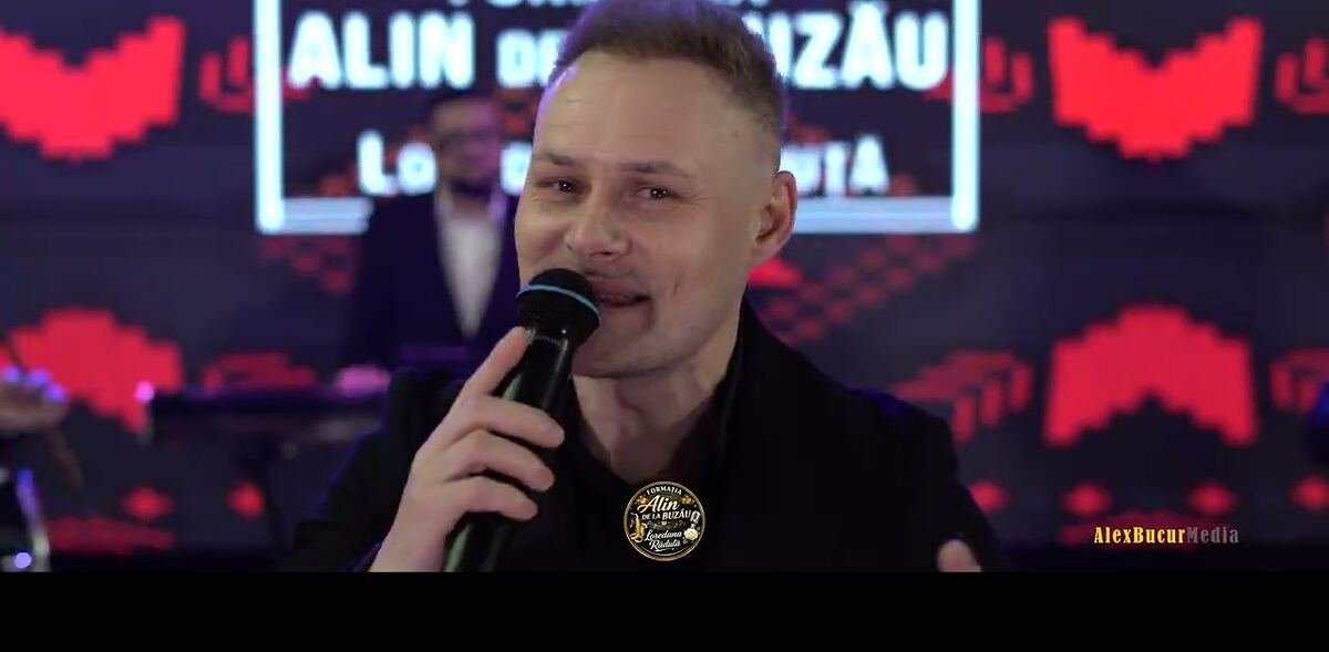 Solist cu microfon în fața unui ecran LED, în timpul unui show live