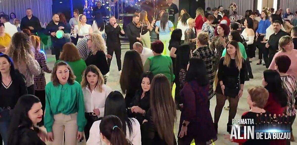 Sală plină de invitați care dansează la muzica formației