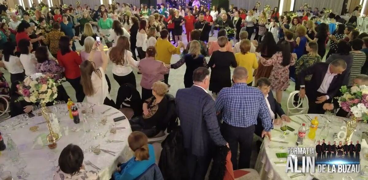 Salon de evenimente plin, cu mesele așezate și invitații pe ring